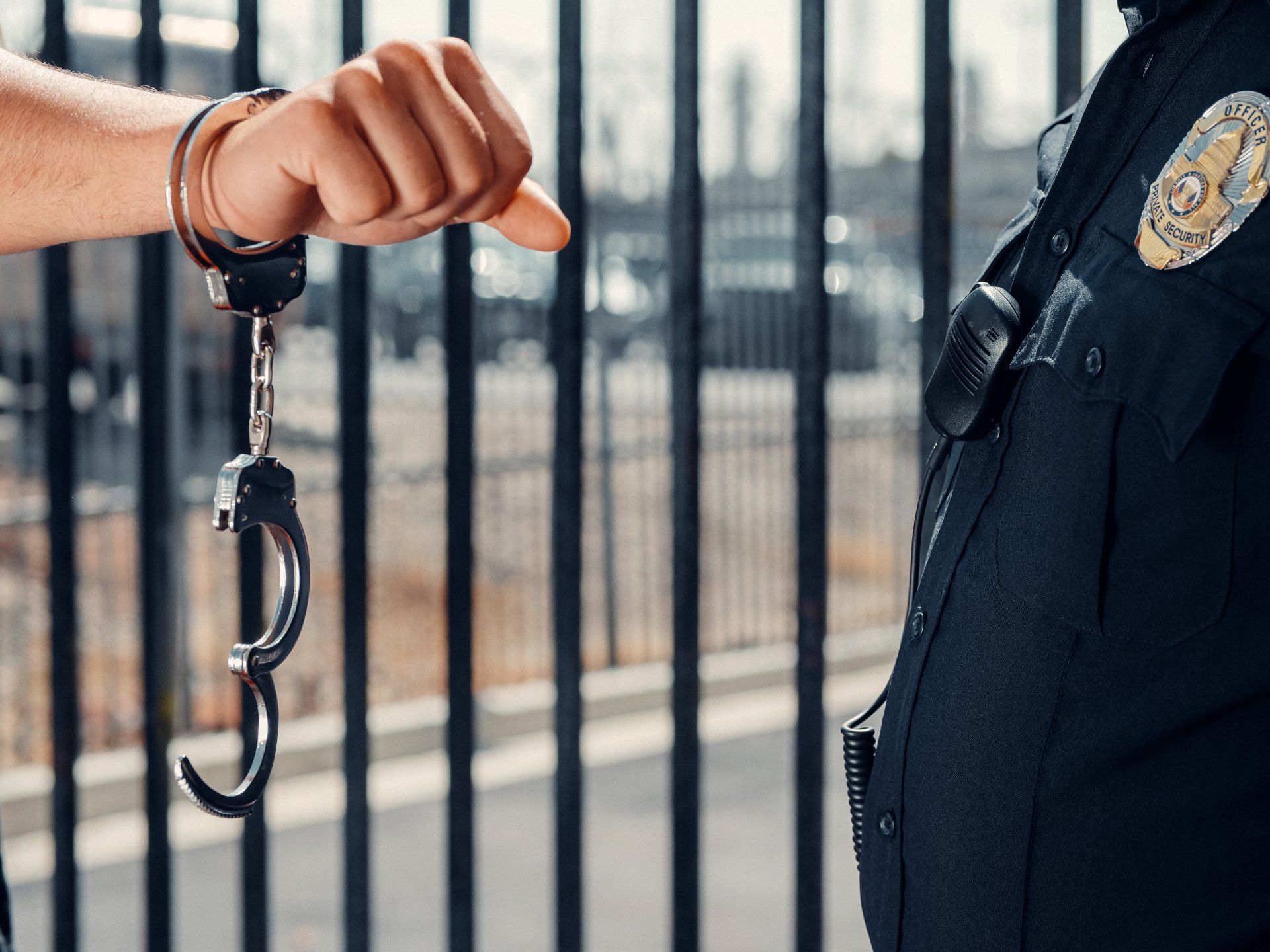 Person with a handcuff on in front of a cop.