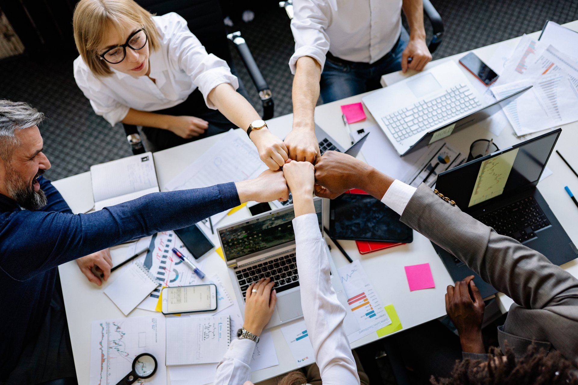 Work team bumping fists over a meeting table