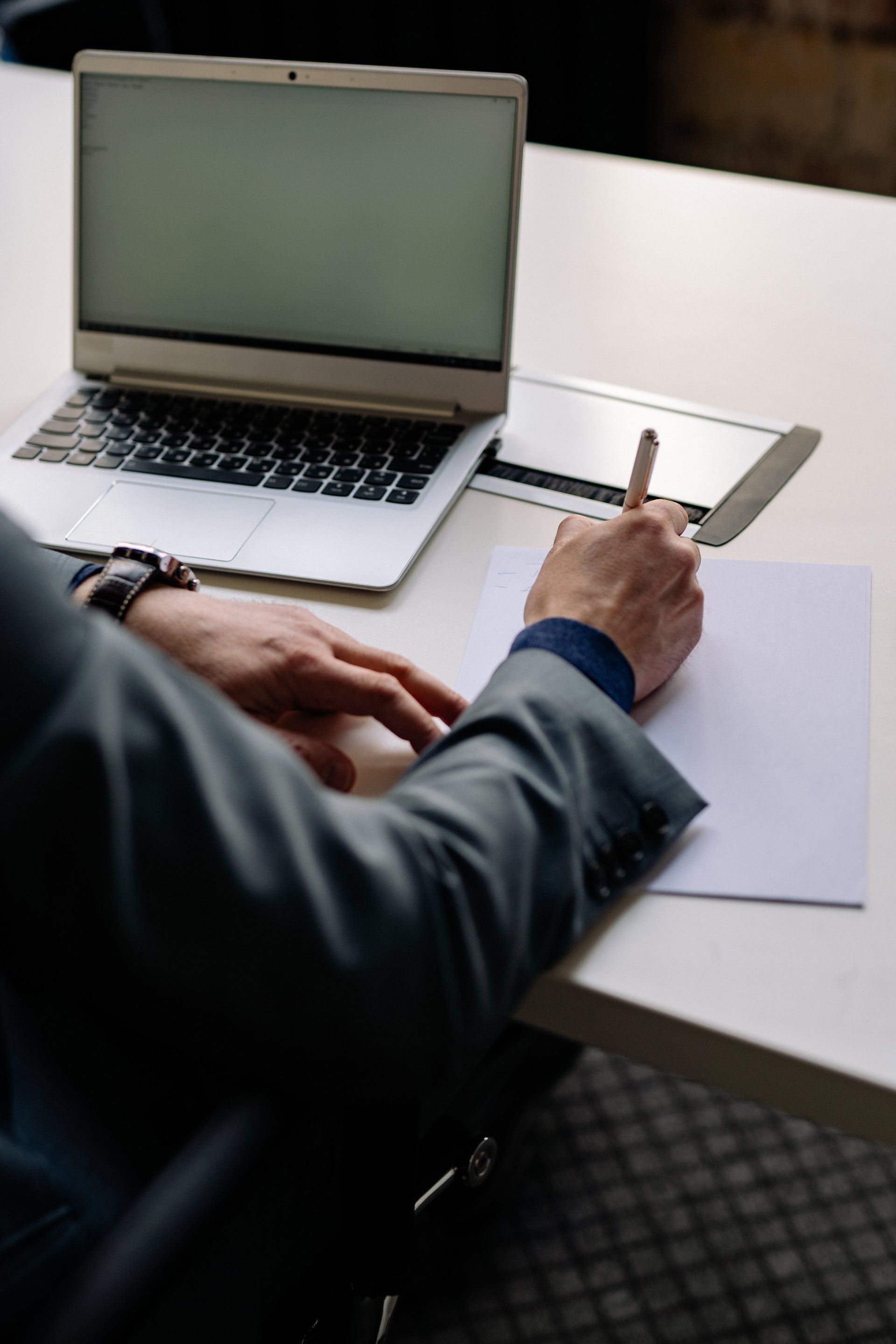 man using laptop computer and taking notes