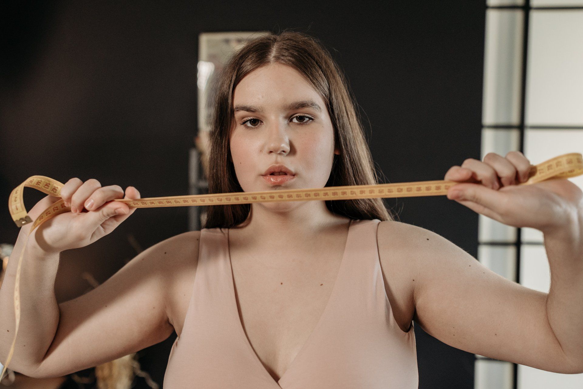 A woman is holding a measuring tape around her neck.