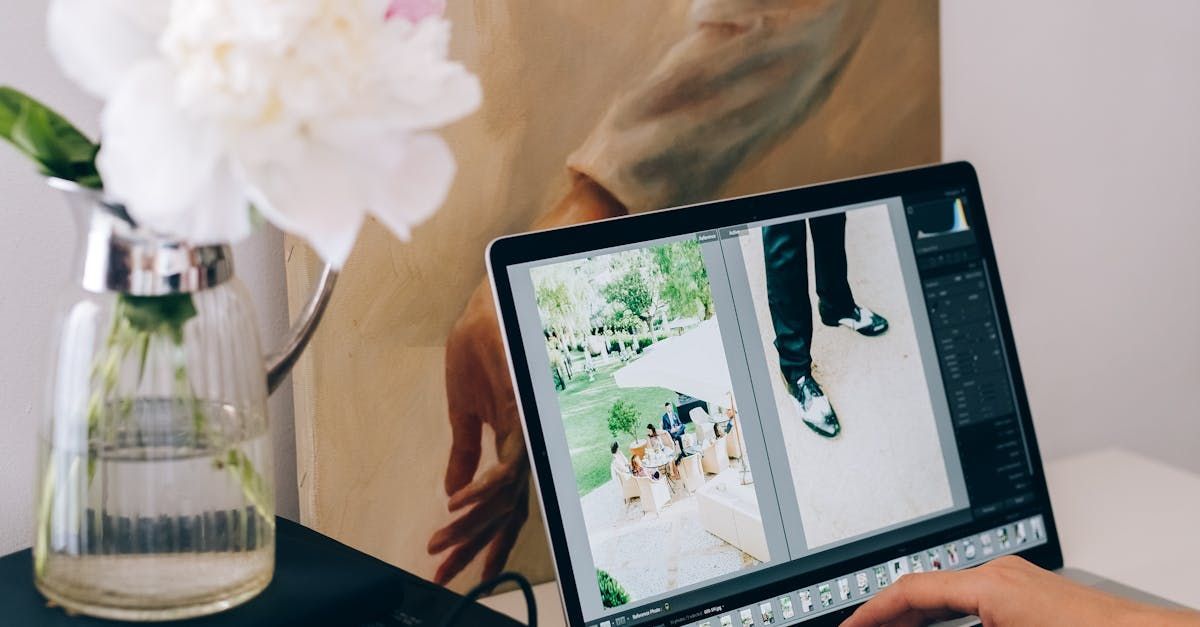 A person is using a laptop computer with a vase of flowers in the background.