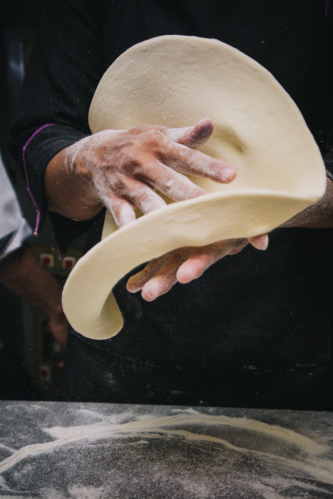 a person is rolling out pizza dough.