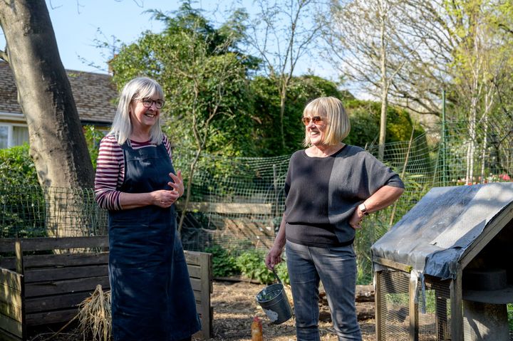 Two women are standing next to each other in a garden.