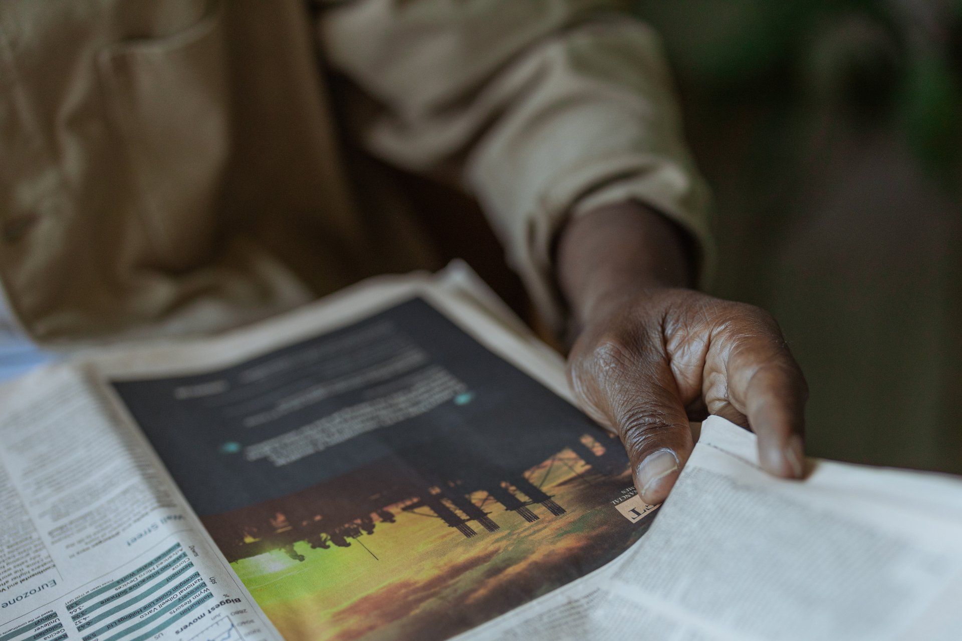 A person is reading a newspaper with a picture of a group of people on it.