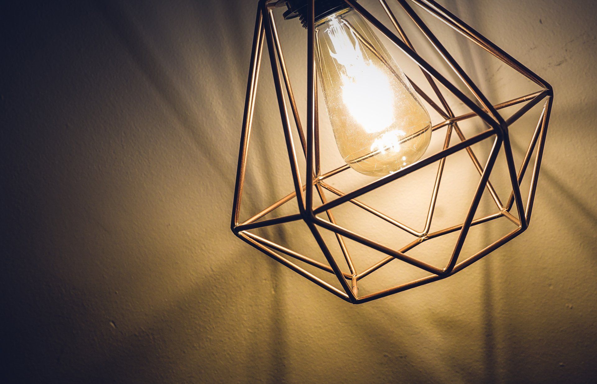 A light bulb is hanging from the ceiling in a geometric cage.