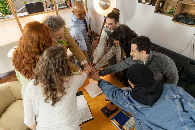 Team of coworkers stacking hands over a table in a bright office meeting room
