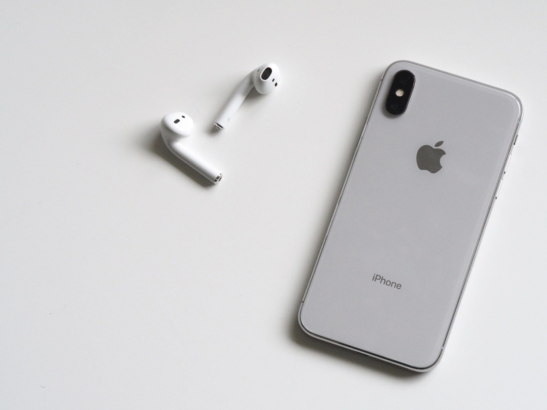 A white apple iphone sitting next to a pair of white ear buds