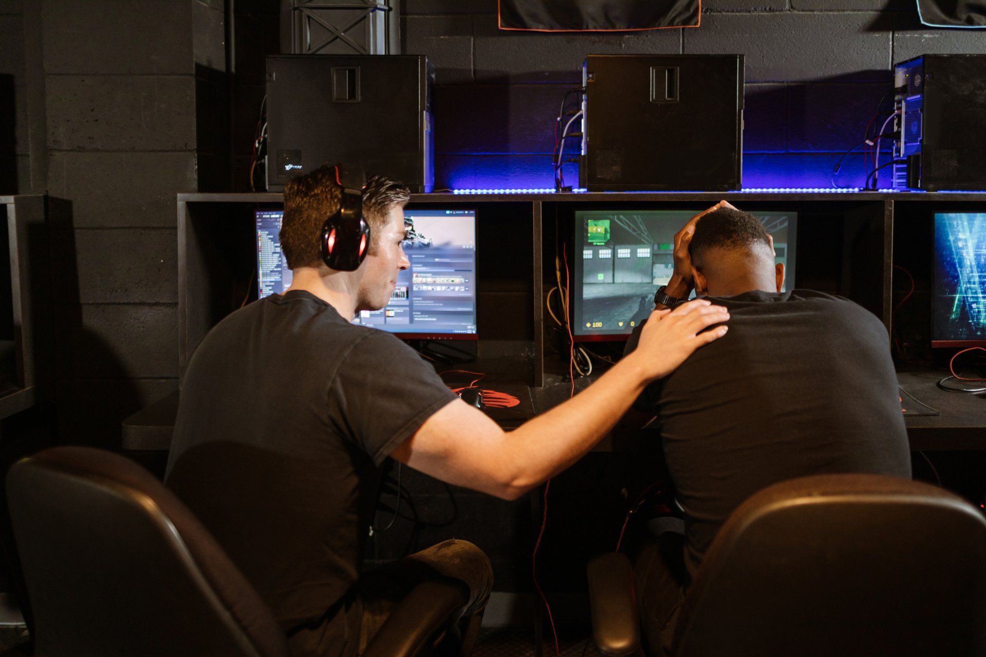 Two men are sitting in front of computer monitors in a room.
