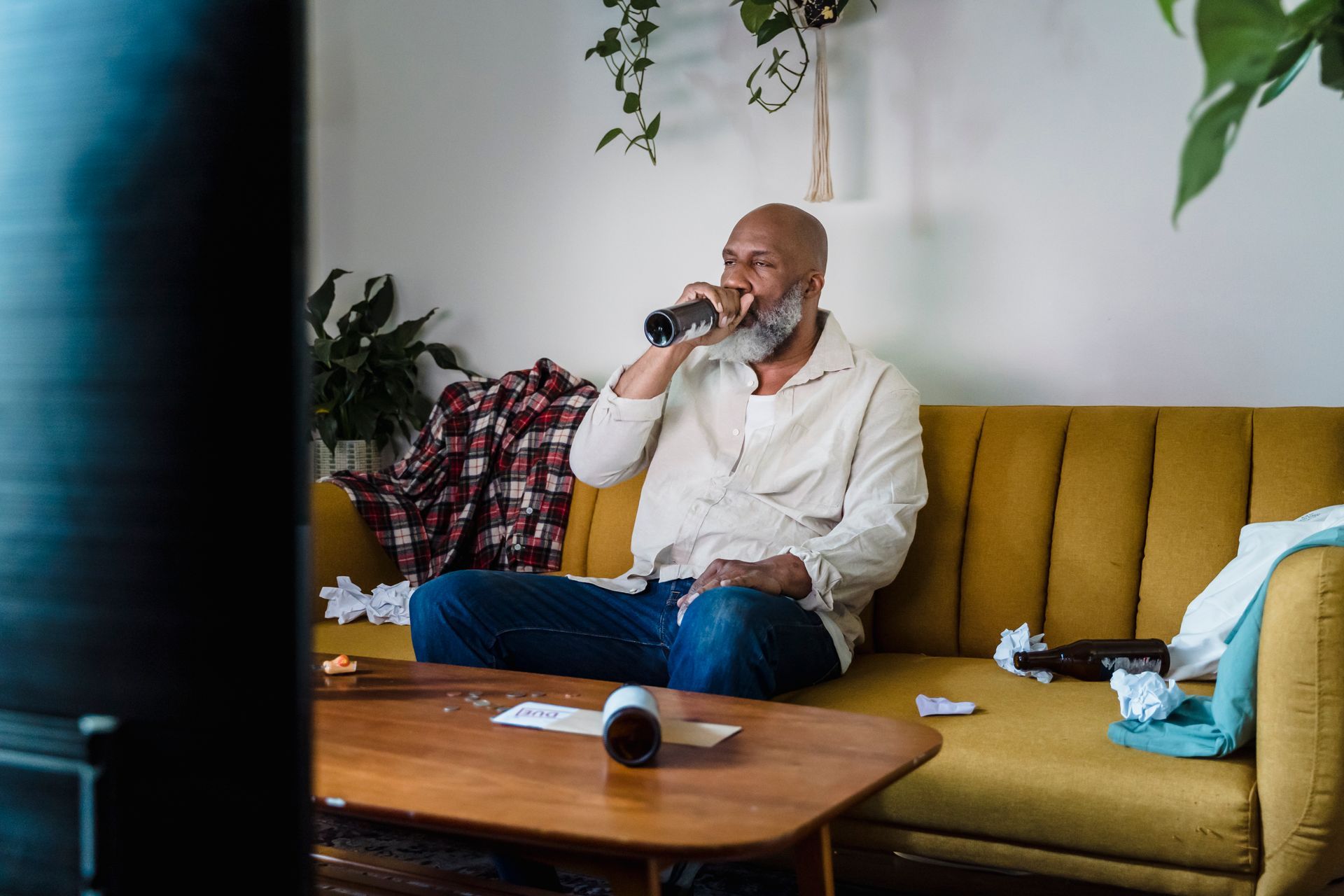 a man is sitting on a couch drinking from a bottle .