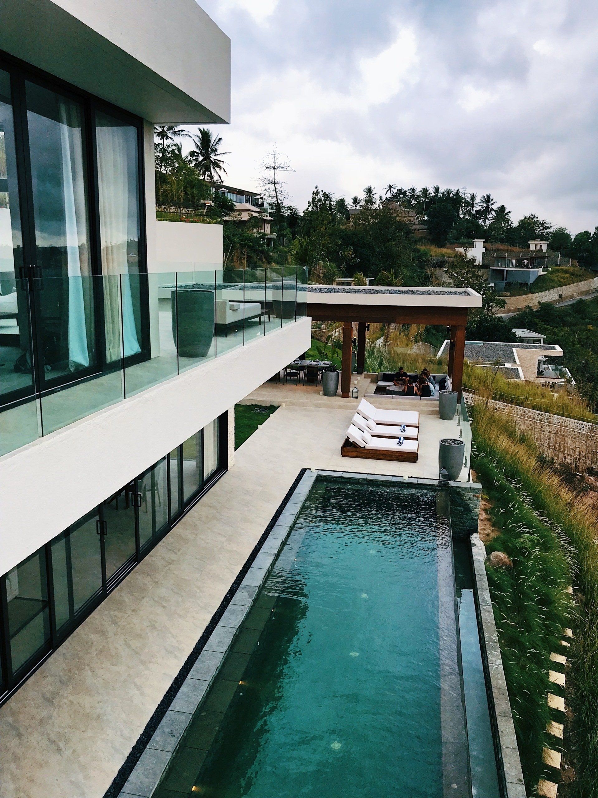 A modern luxury villa with a lap pool and a luxurious-looking concrete pool deck.