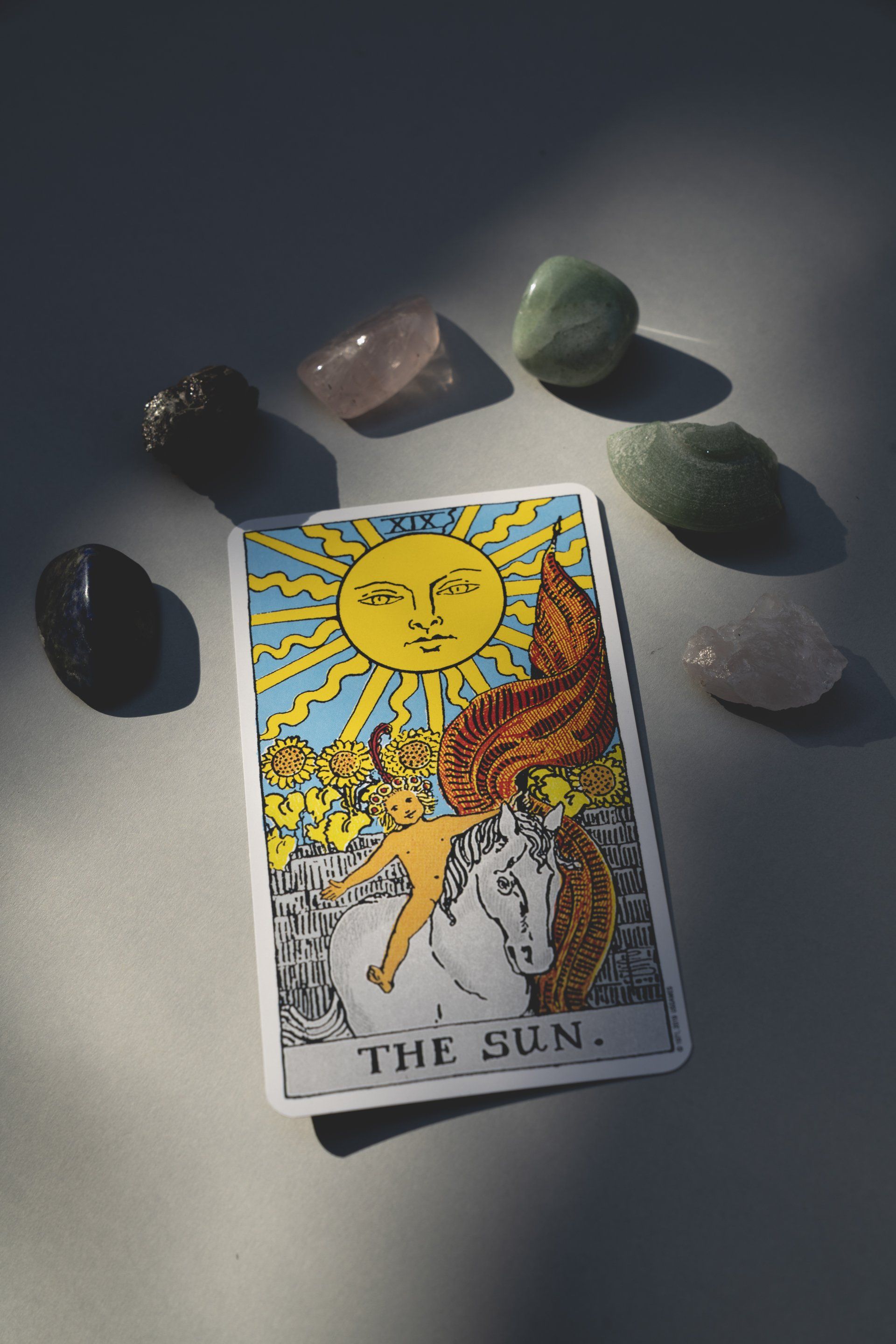 A carta de tarô do sol está cercada por cristais sobre uma mesa.