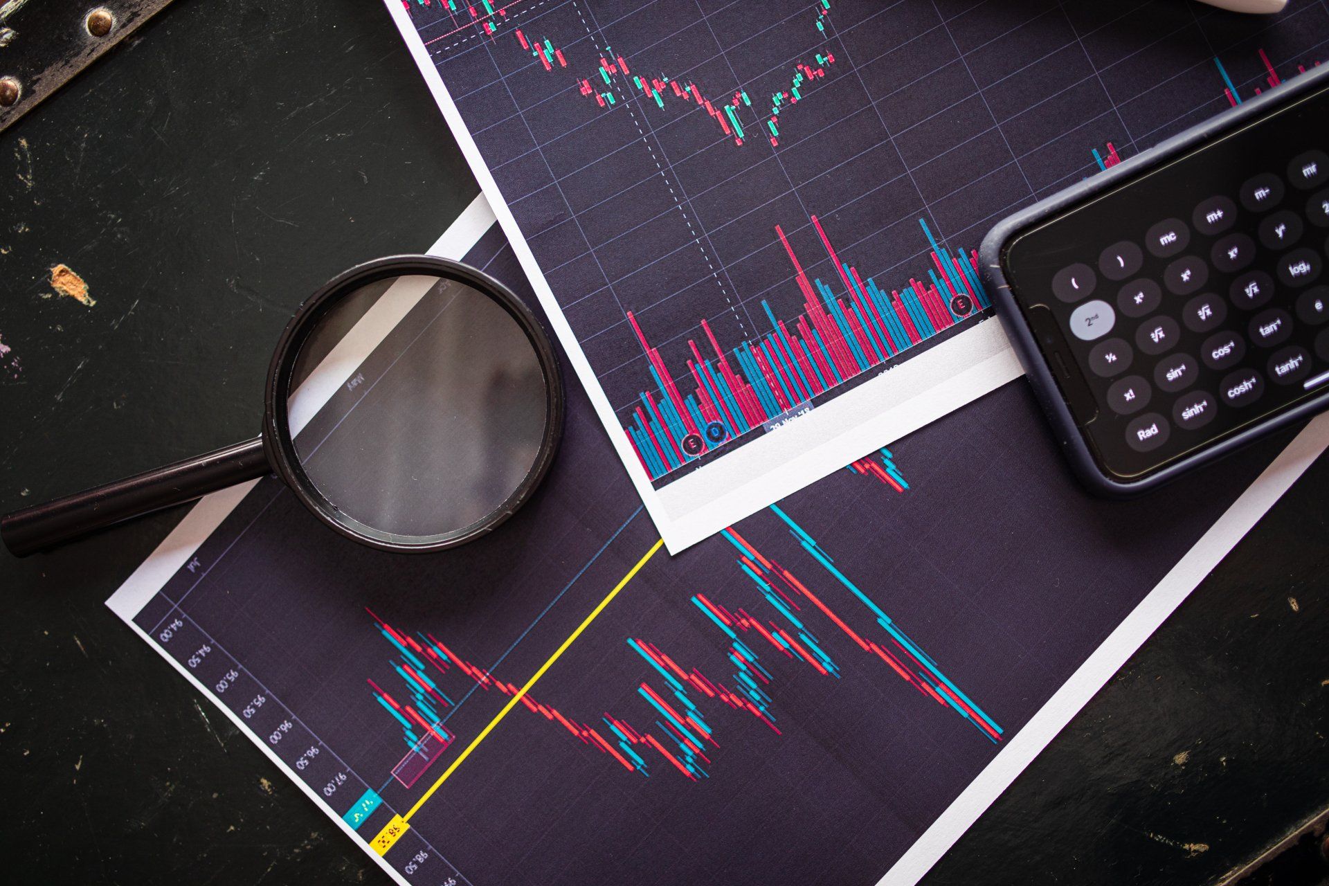A magnifying glass is sitting on top of a graph next to a calculator.