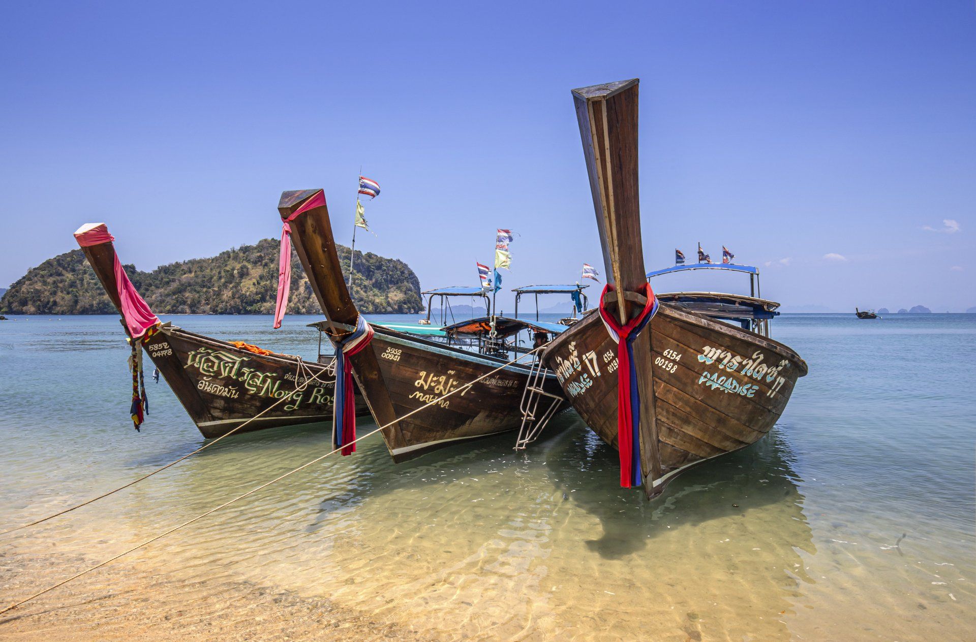 Longtail boats resting on the shore in Krabi, Thailand with Hong Island Lagoon in the background.