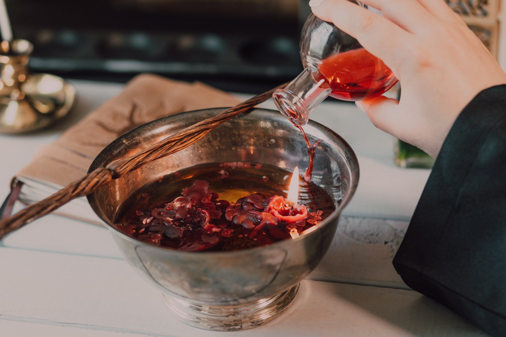 A person is pouring liquid into a bowl of candles.