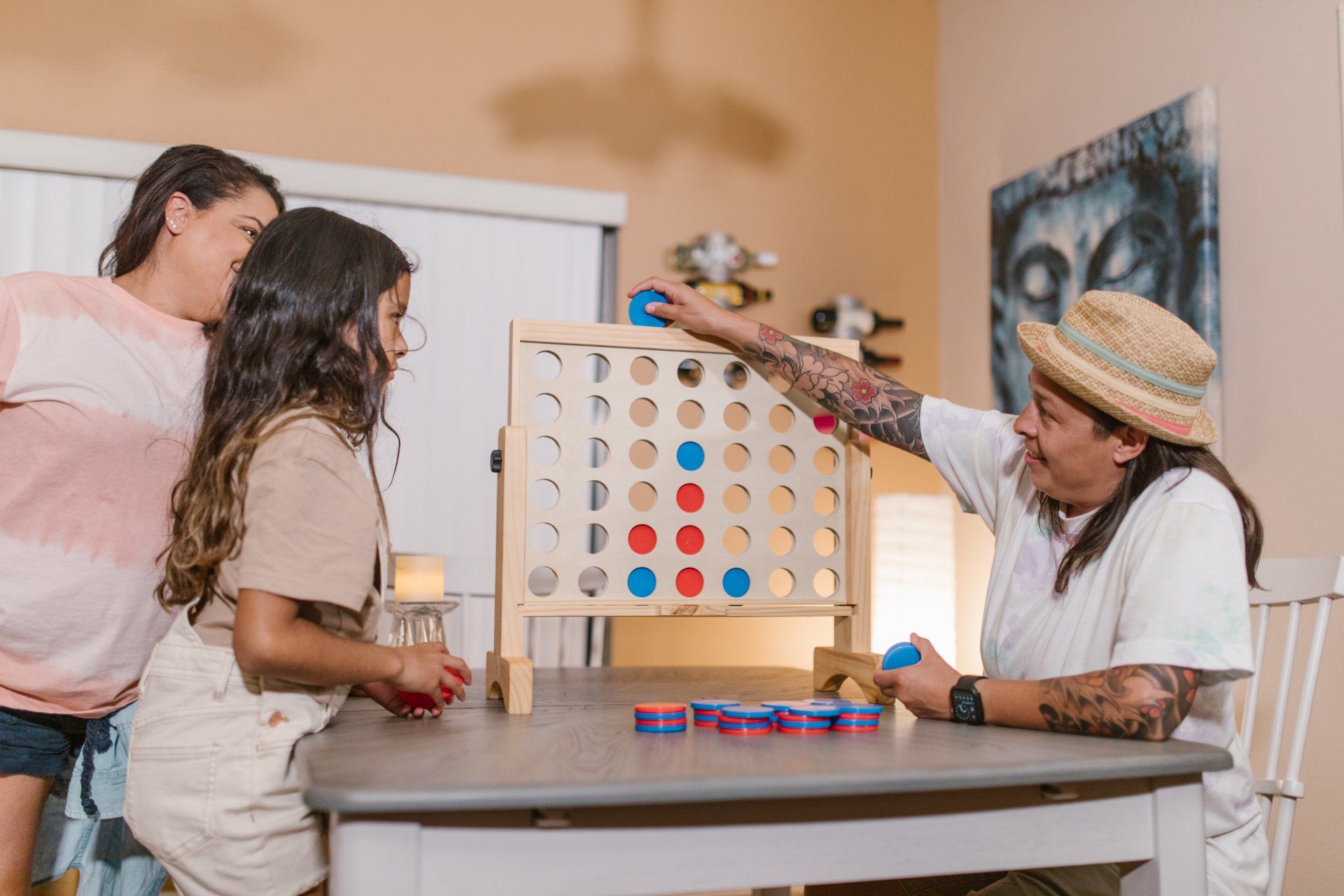 A man and two girls are playing a game of connect four at a table.