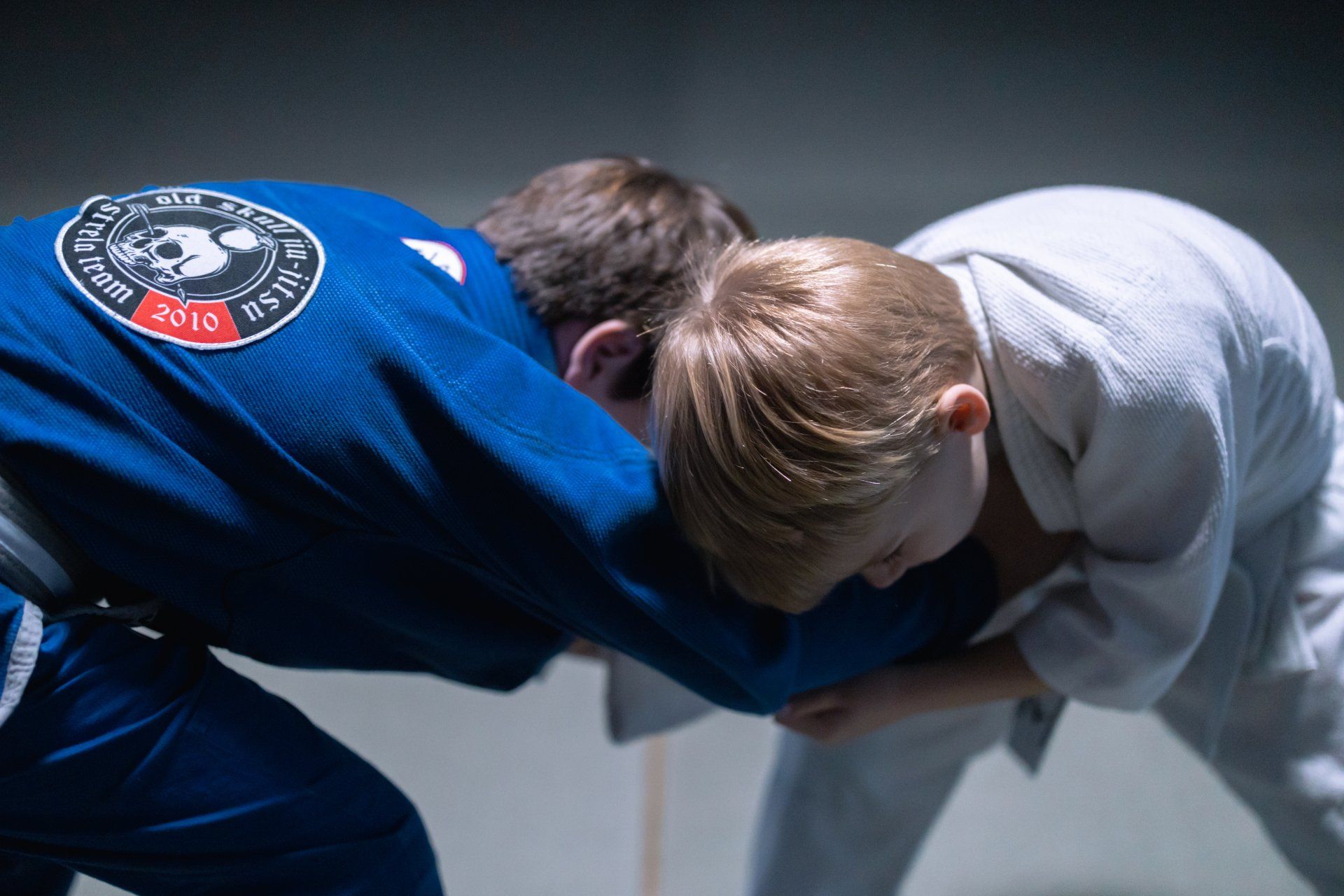 Two young boys are practicing judo in a dark room.