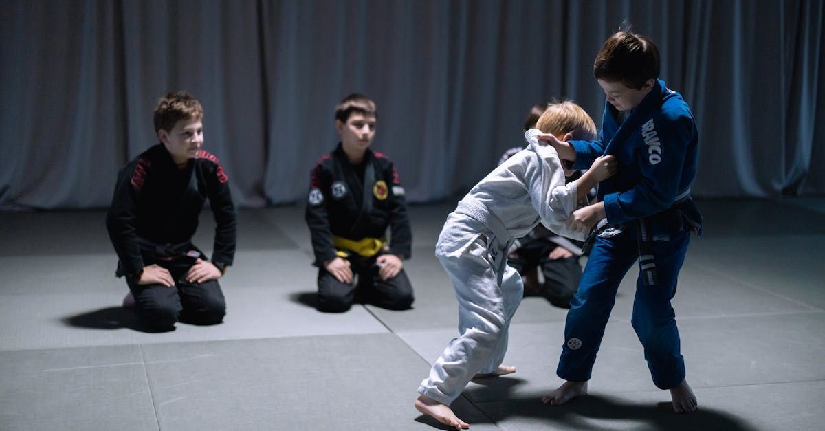 A group of young boys are practicing jiu jitsu in a gym.
