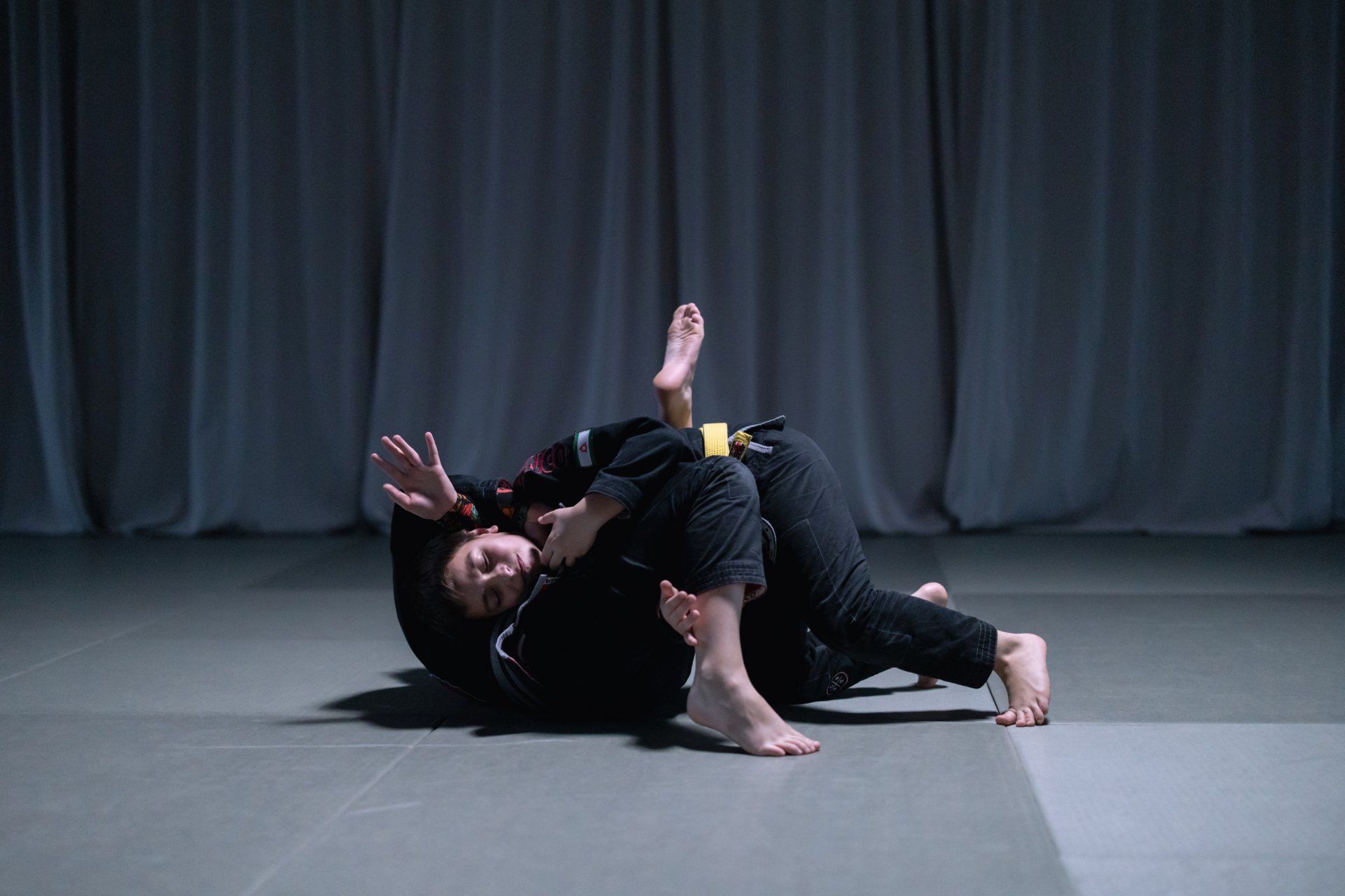 a person with a yellow belt is laying on another person 's back