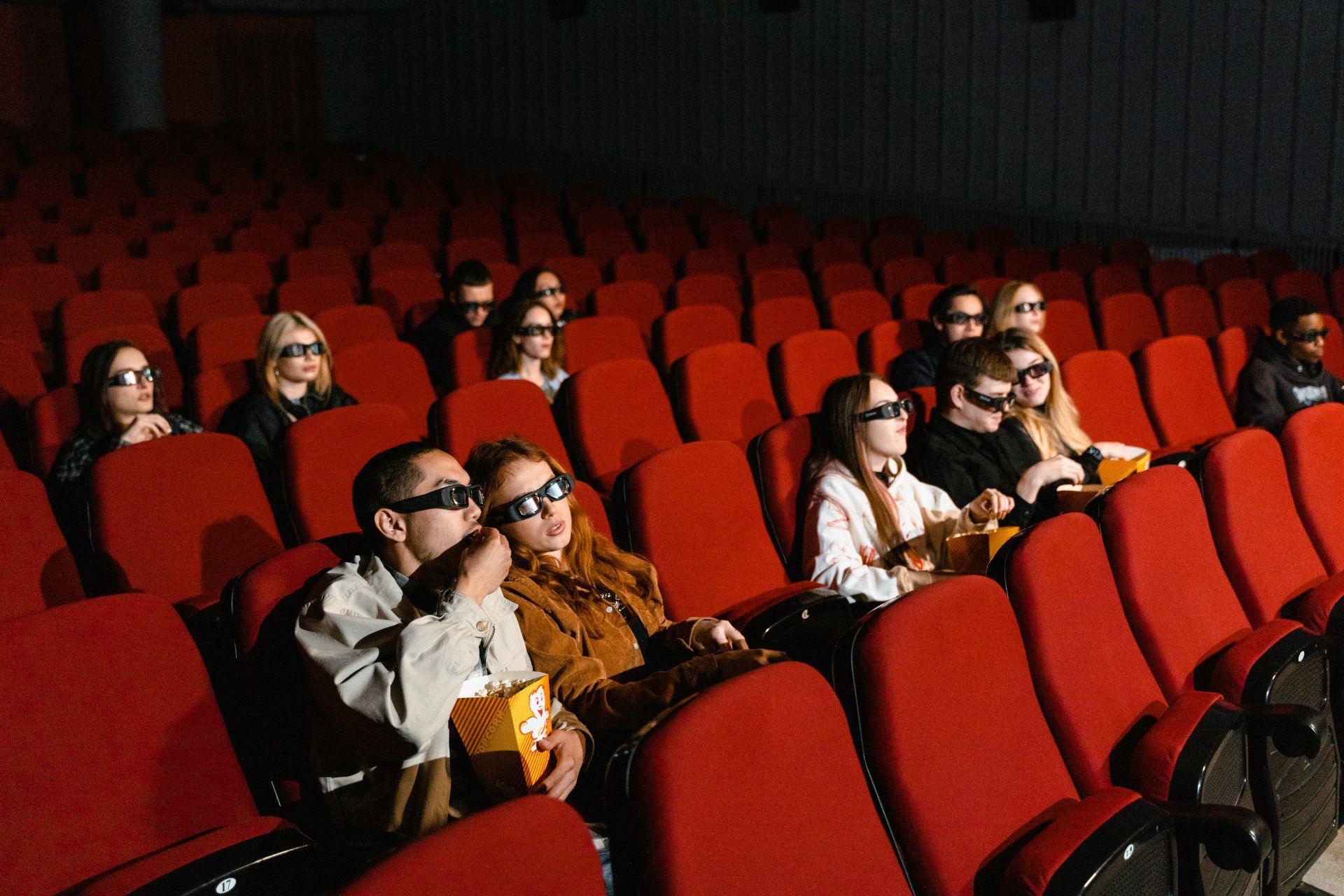 Um grupo de pessoas está sentado em um cinema assistindo a um filme.
