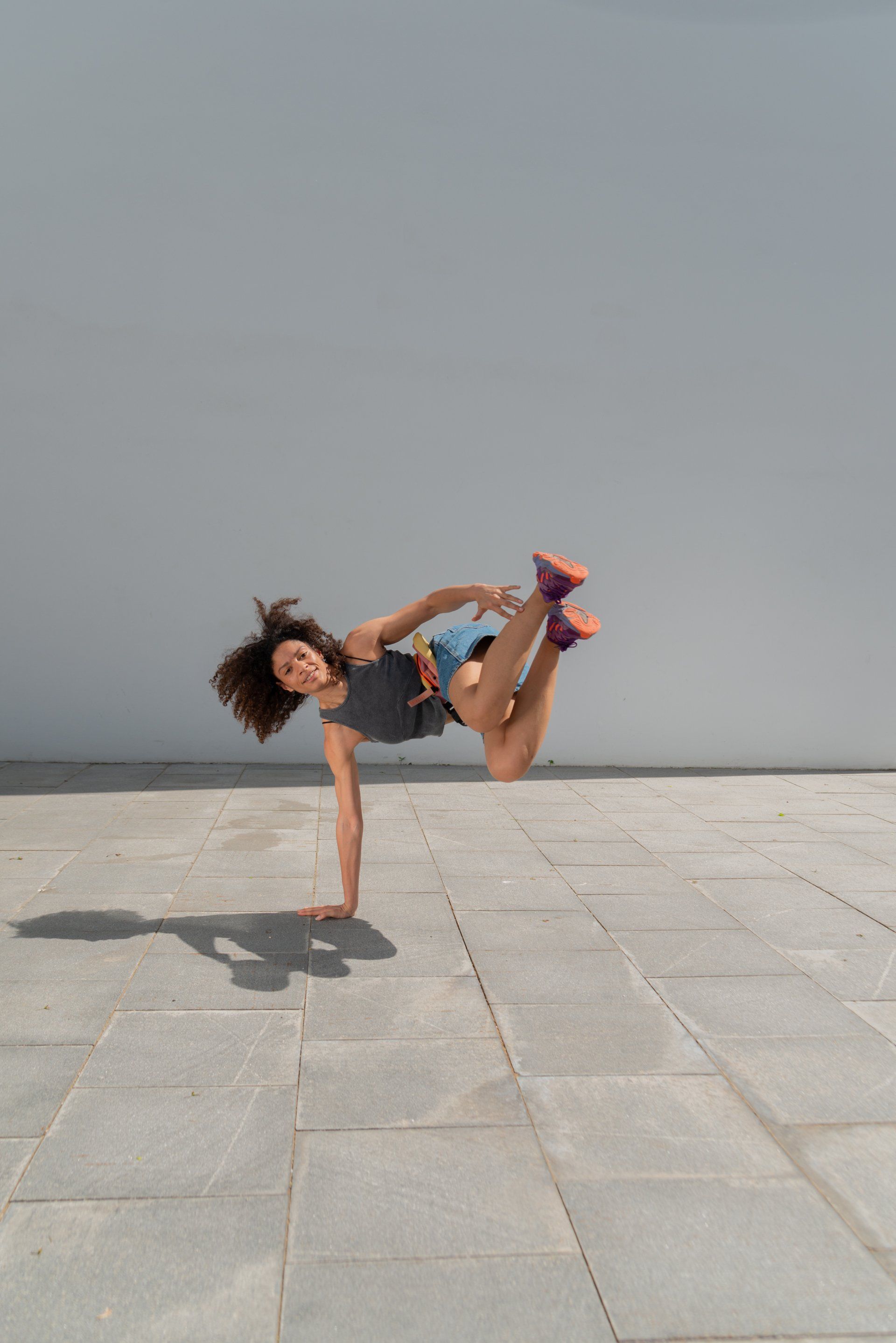 Een vrouw doet een handstand op de stoep.