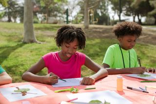 Non-Profit Organizations and Education A group of children are sitting at a table in a park.