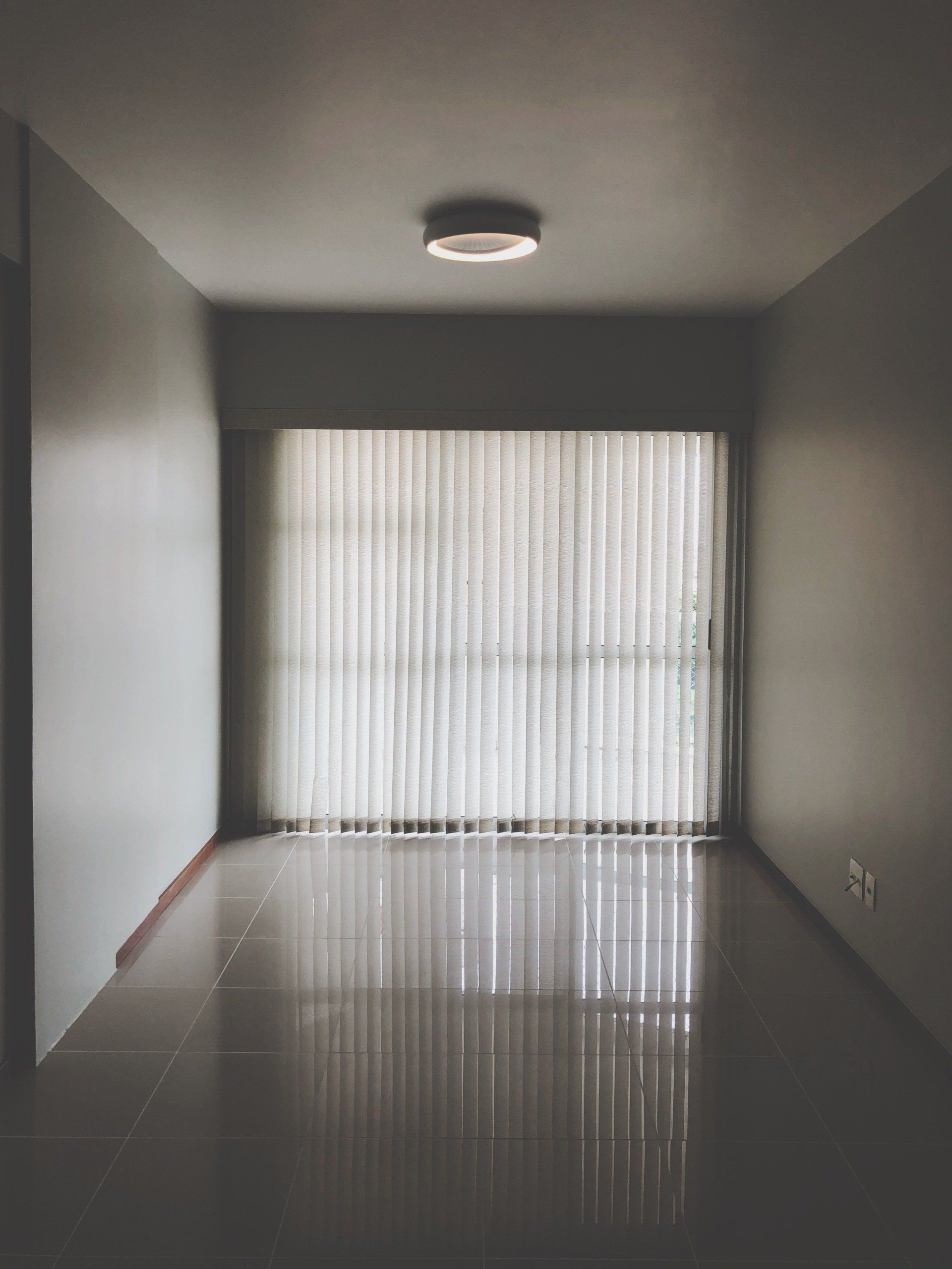 An empty room with a large window and blinds