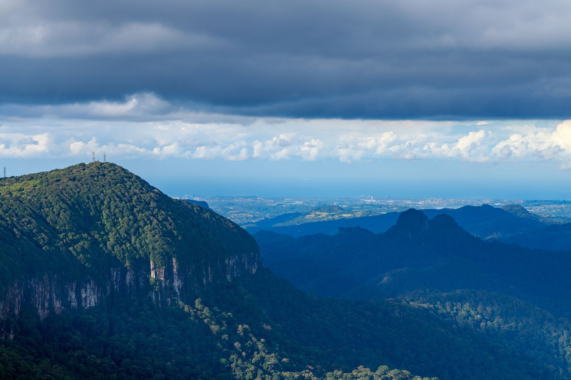 An aerial view of a mountain range with a cloudy sky in the background.