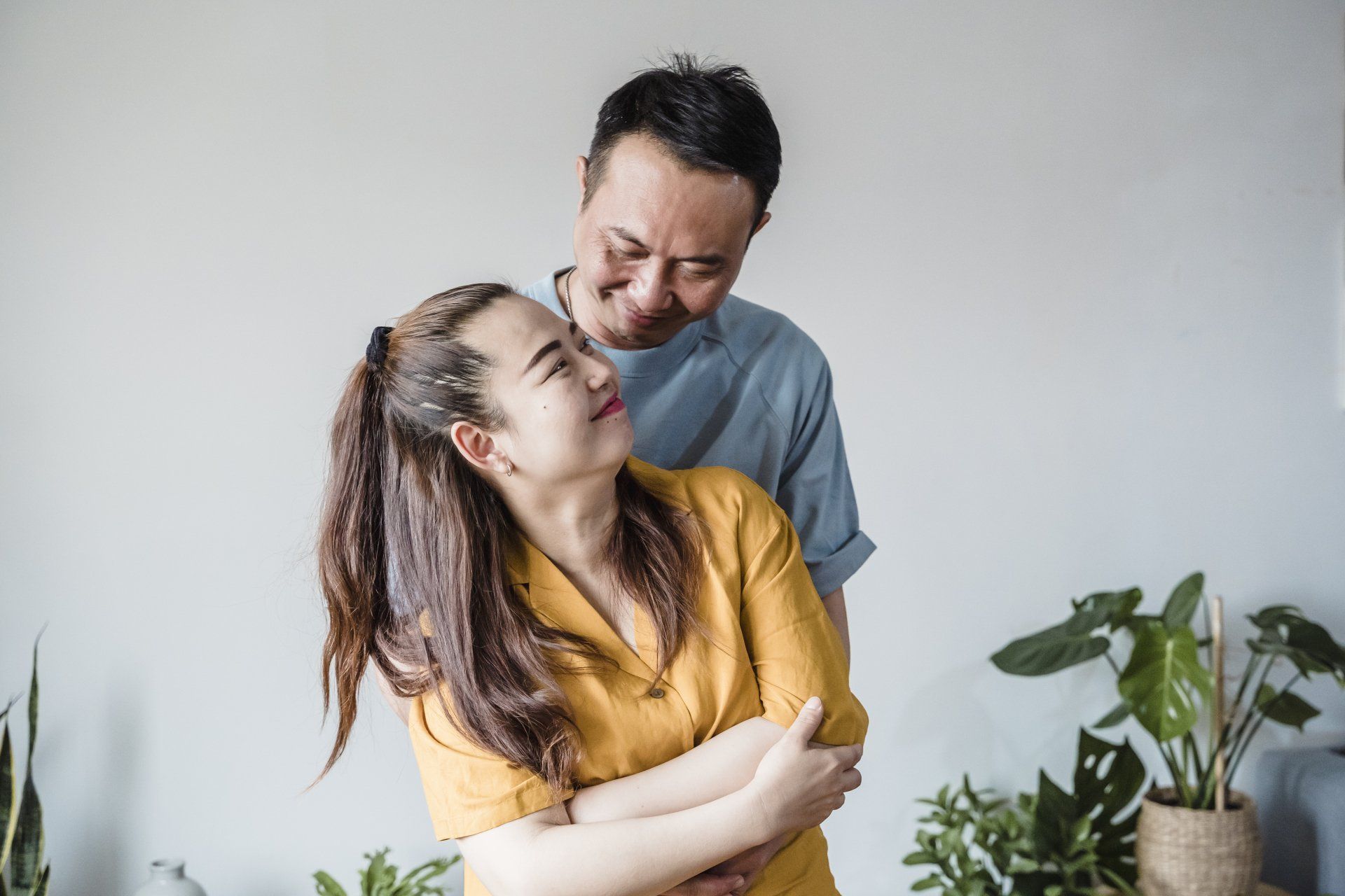 A man and a woman are hugging each other in a living room.