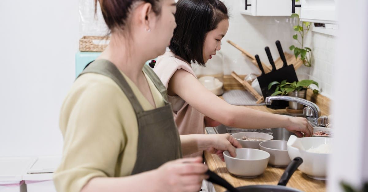 A woman and a child are washing dishes in a kitchen. SIL – Supported Independent Living, NDIS, Canberra
