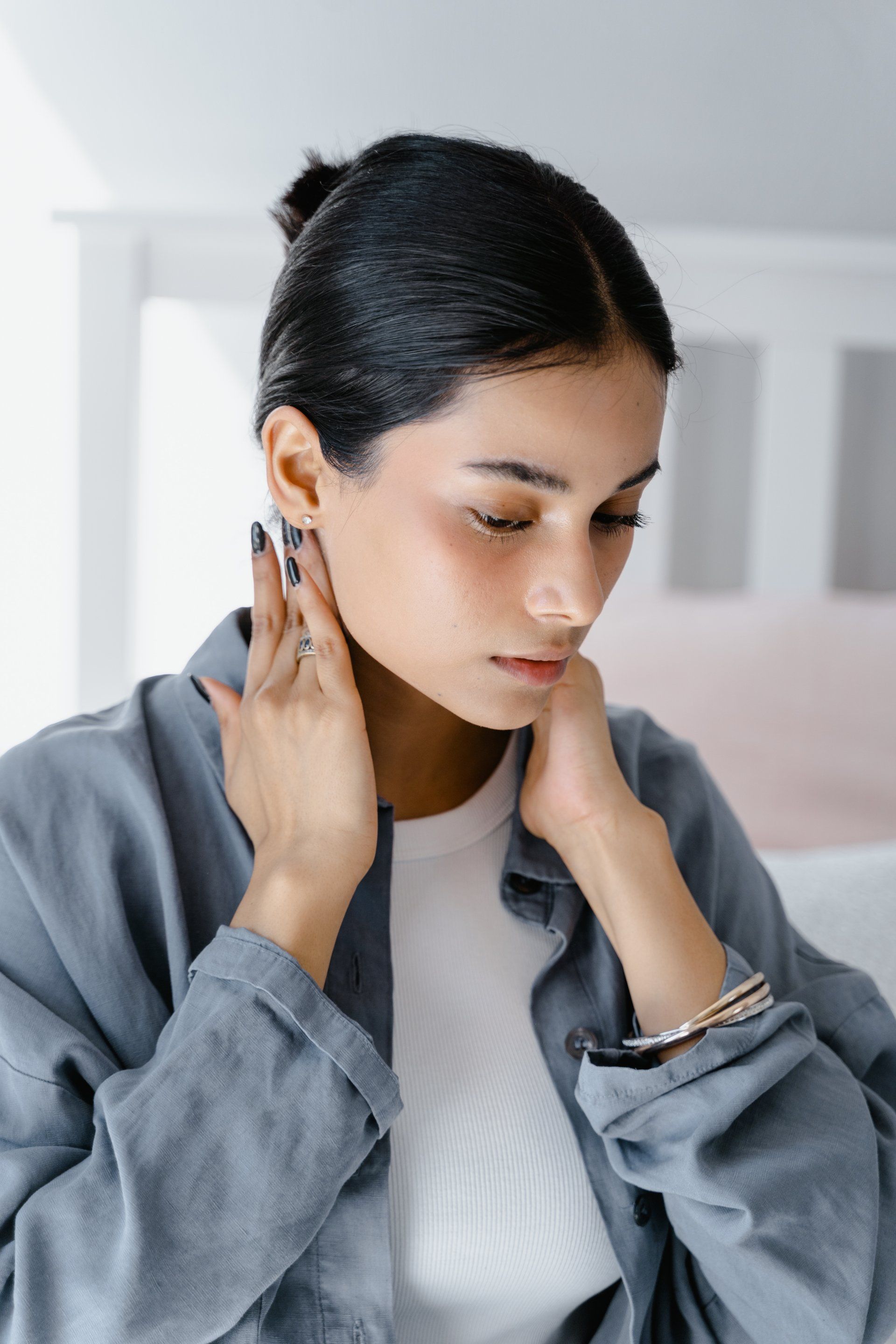 A woman is touching her ear while wearing earrings.