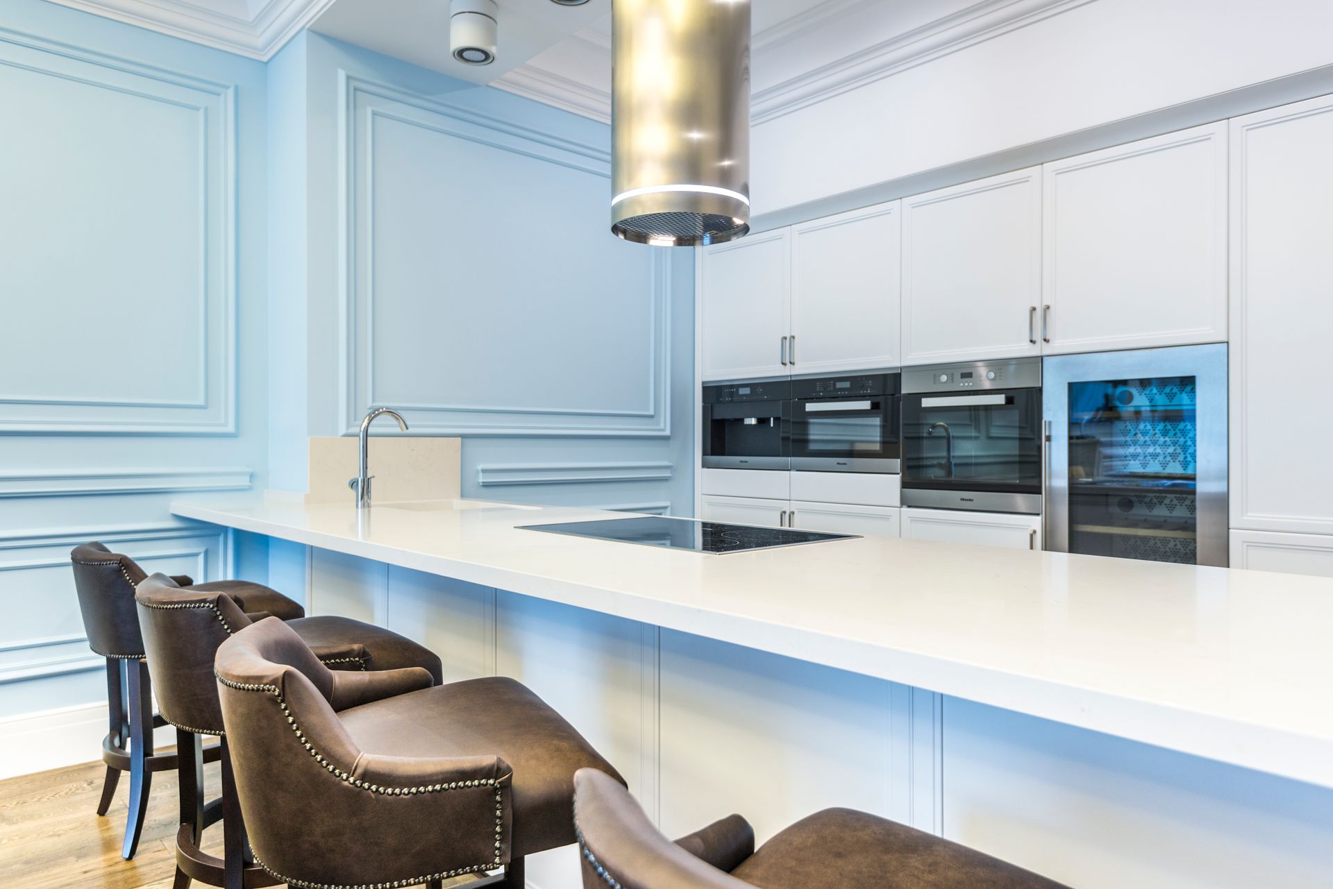 a kitchen with white cabinets and stools and a long counter .