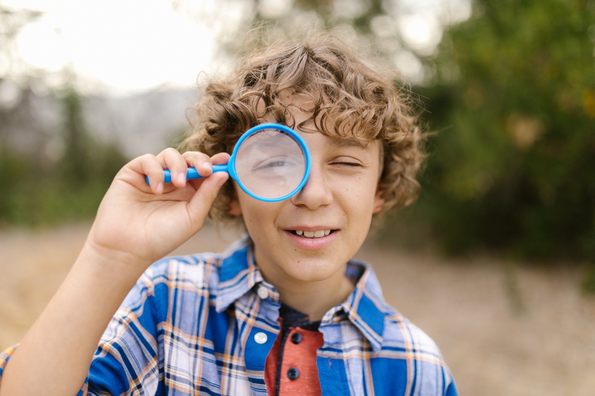 A young boy is looking through a magnifying glass.