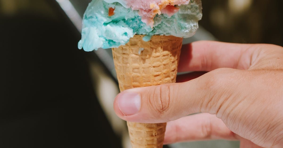 Hand holding a waffle cone with a scoop of blue and pink ice cream. Grasshopper Farms Knightdale, NC