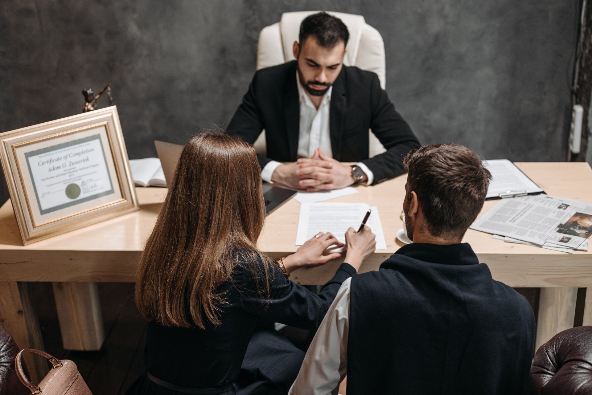 A man and a woman are sitting at a table talking to a lawyer.