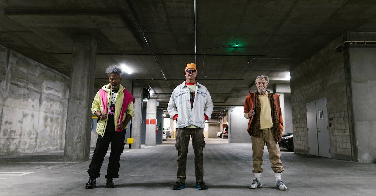 Three men are standing next to each other in a parking garage.