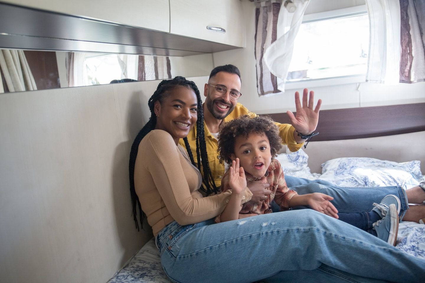 A family is sitting on a bed in a camper.