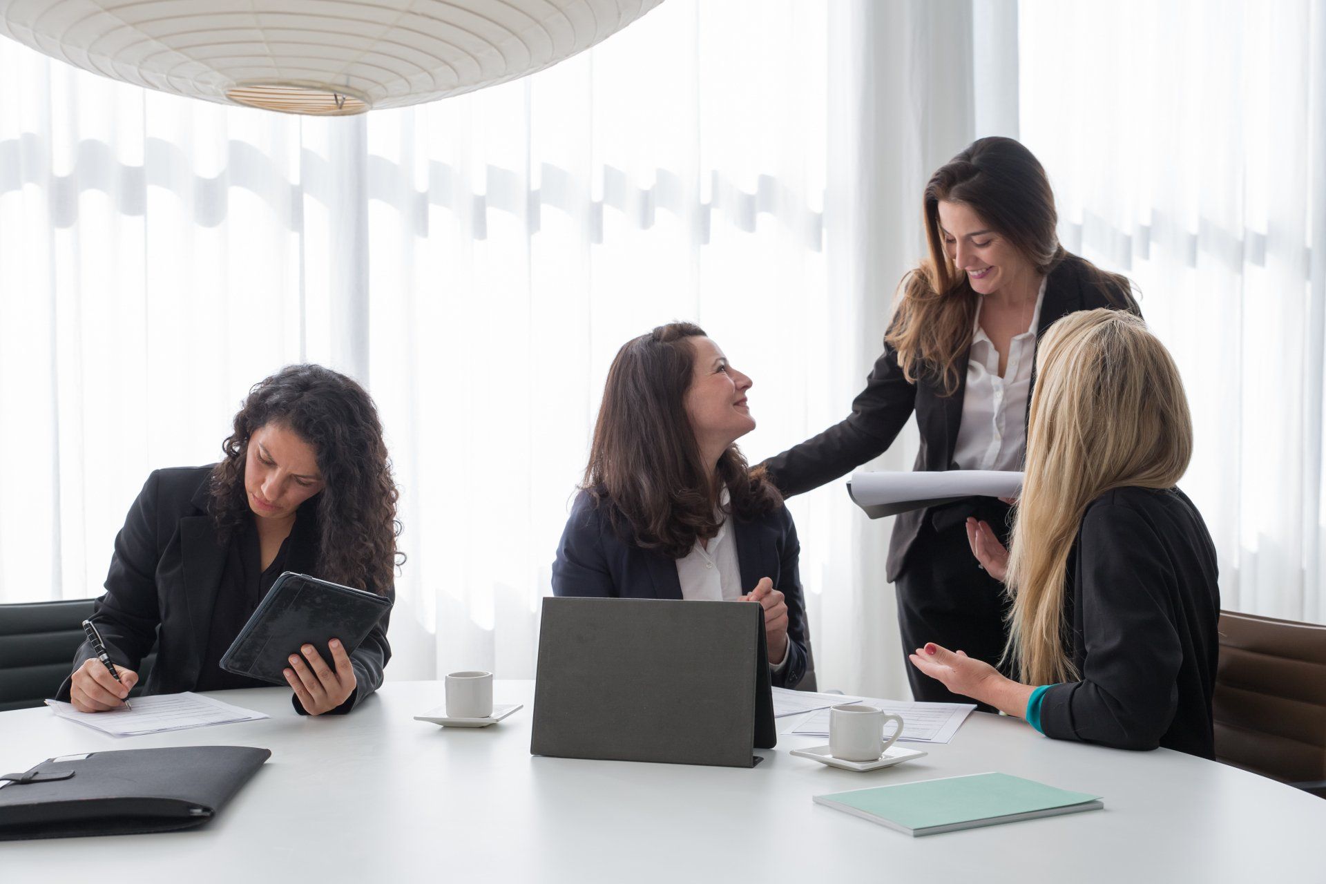 A group of women are sitting around a table with laptops.