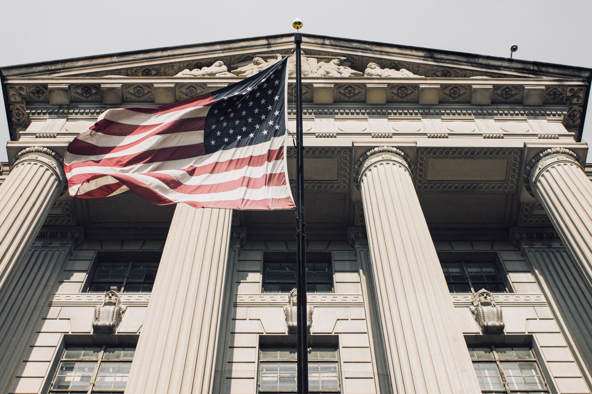 An american flag is flying in front of a large building.