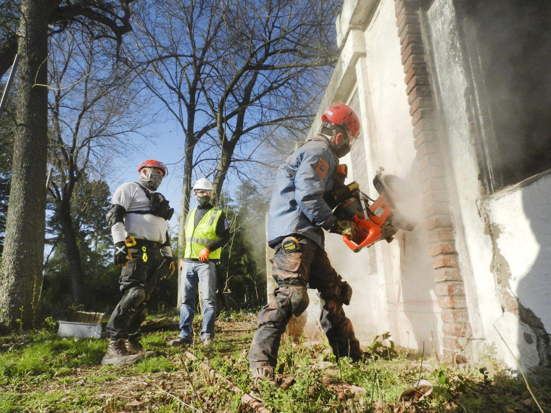 A man is cutting a hole in a wall with a chainsaw.