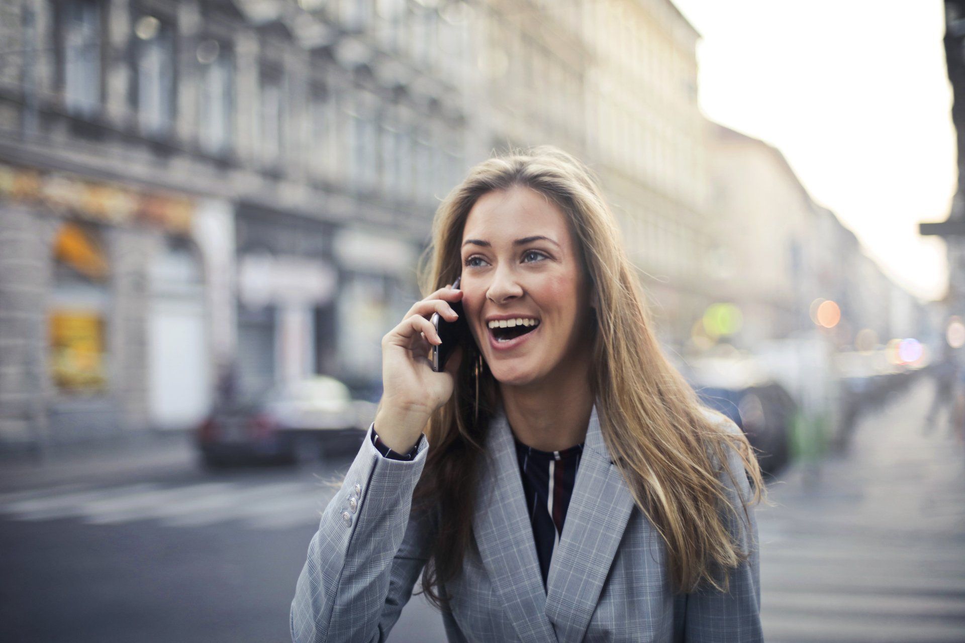 A woman is talking on a cell phone while walking down the street.
