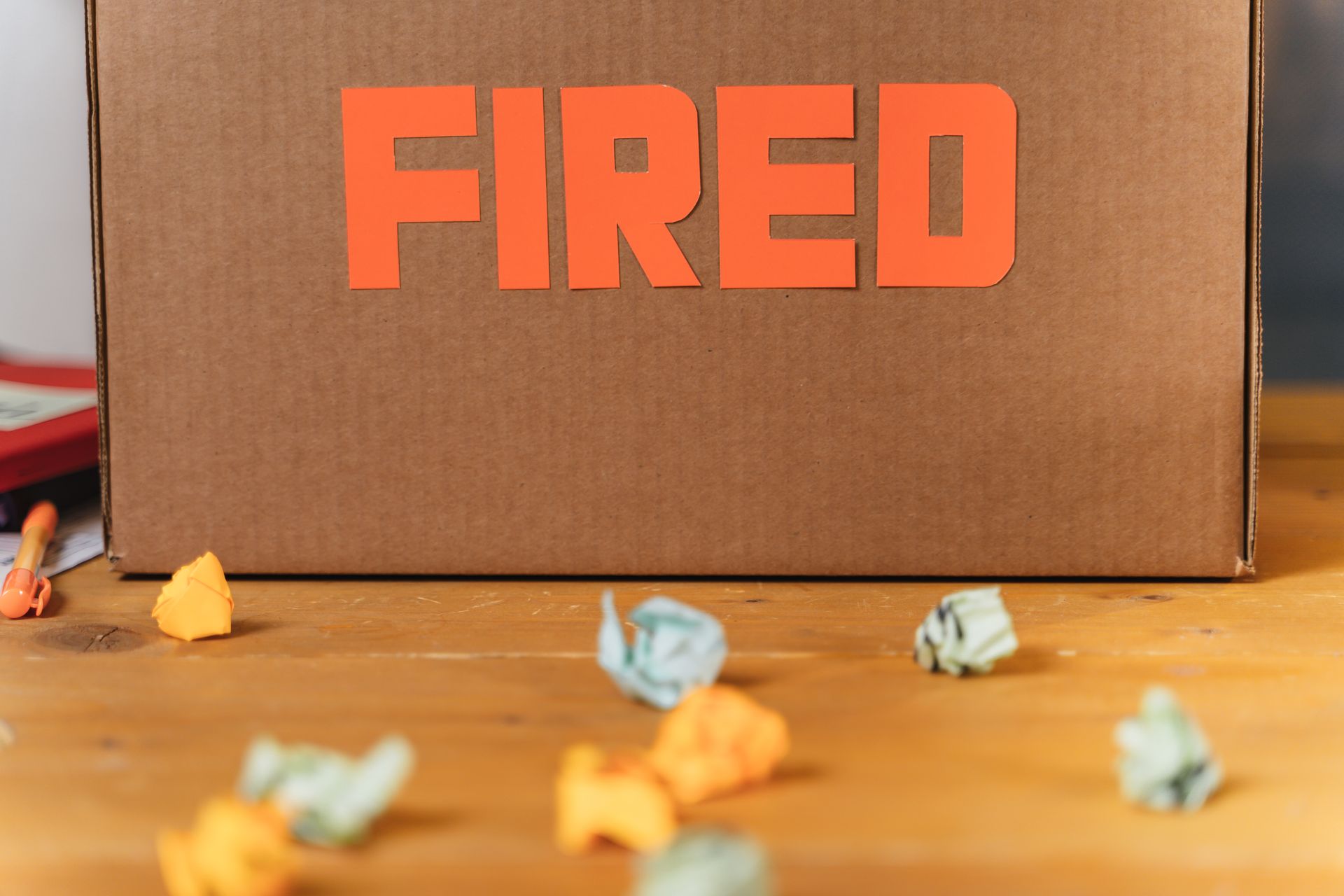 A cardboard box with the word fired written on it is on a wooden table.