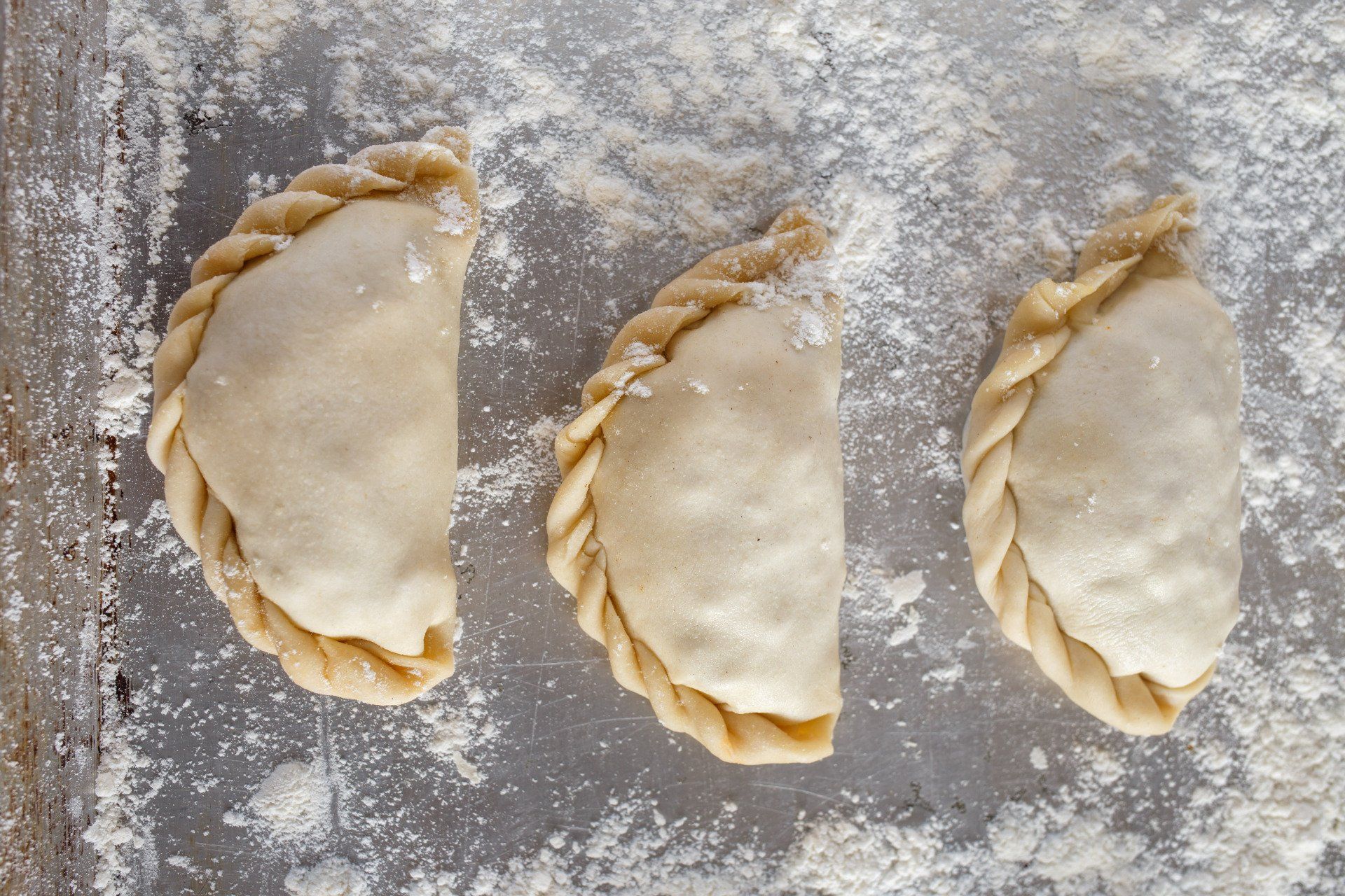 Three pastries are sitting on a pan covered in flour.