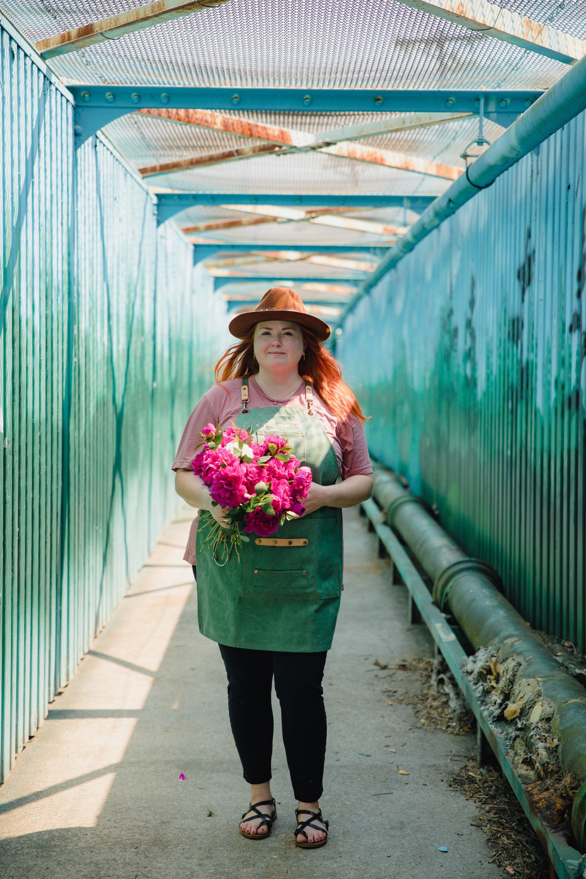 Una mujer está parada en un pasillo sosteniendo un ramo de flores rosas.