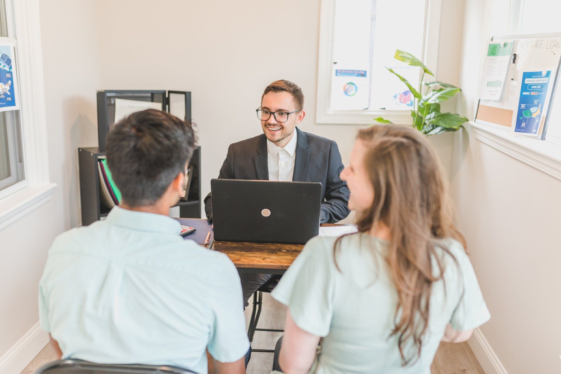 A man is sitting at a desk talking to two people.