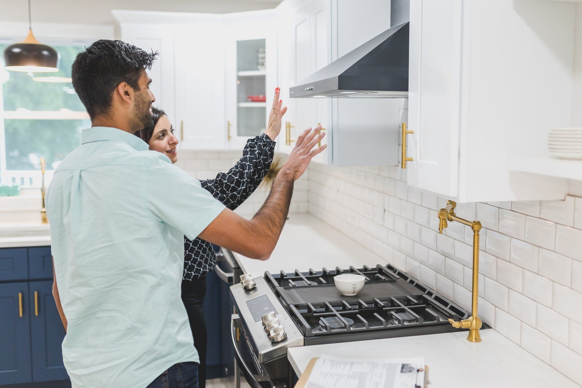 a man and a woman are standing in a kitchen looking at a stove . Fresno appliance repair