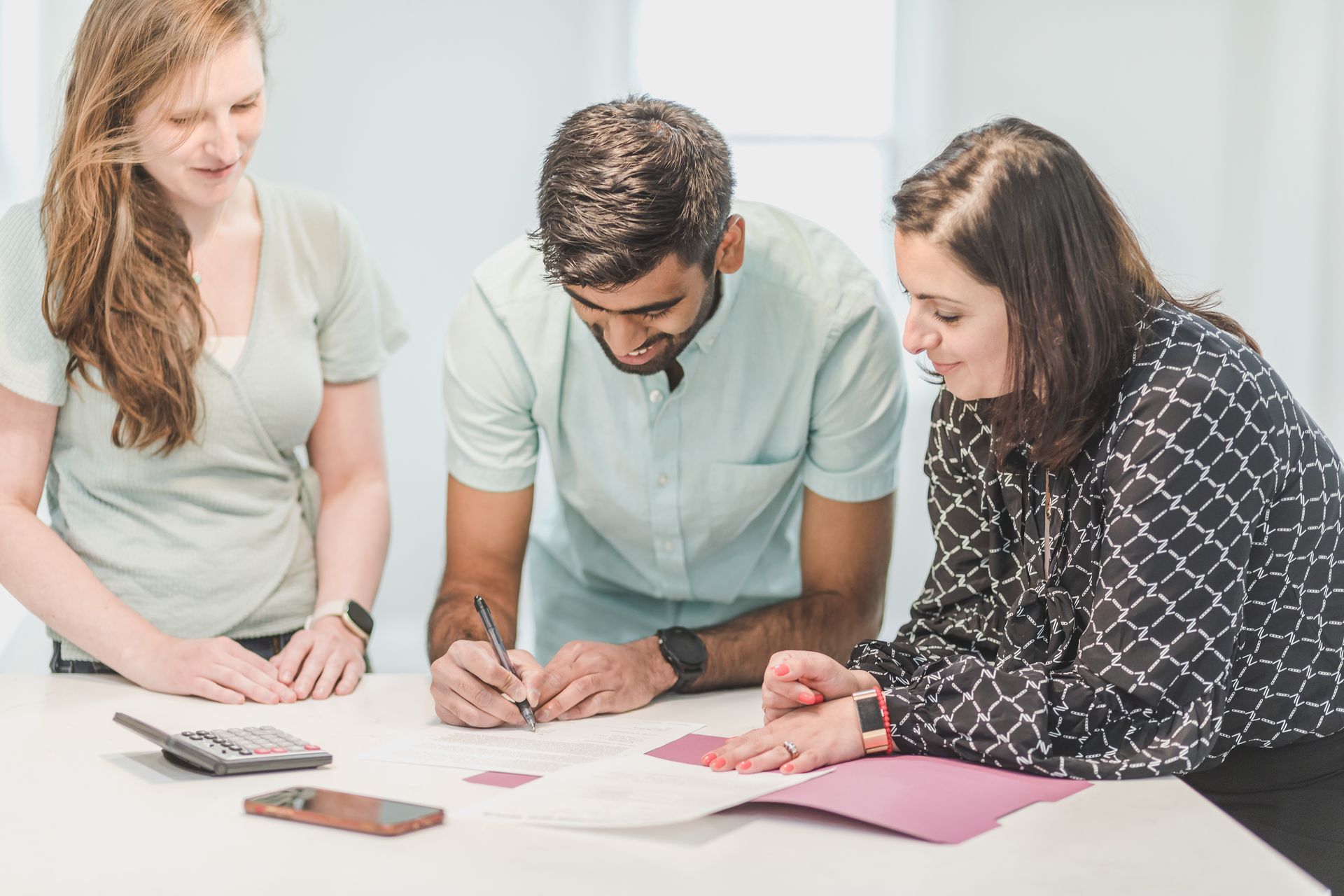 A group of people are sitting around a table looking at a piece of paper.