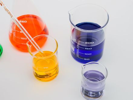 A pipette is being poured into a beaker of yellow liquid