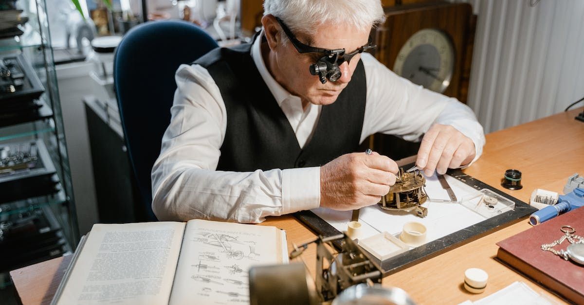 A man wearing magnifying glasses is working on a clock.