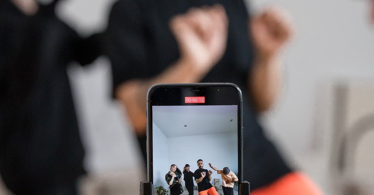 A person is holding a cell phone in front of a group of people dancing.