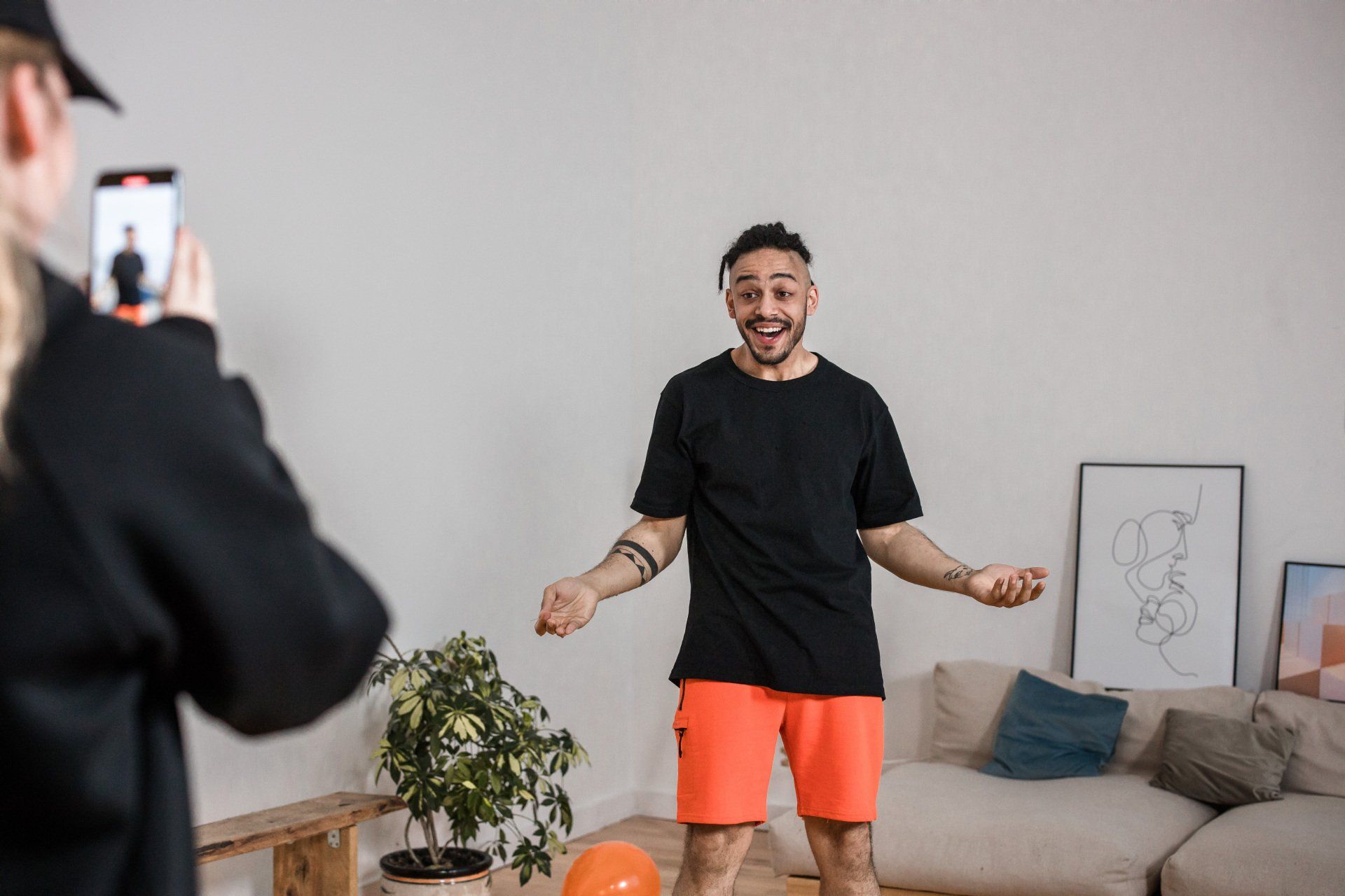 A woman is taking a picture of a man in a living room.